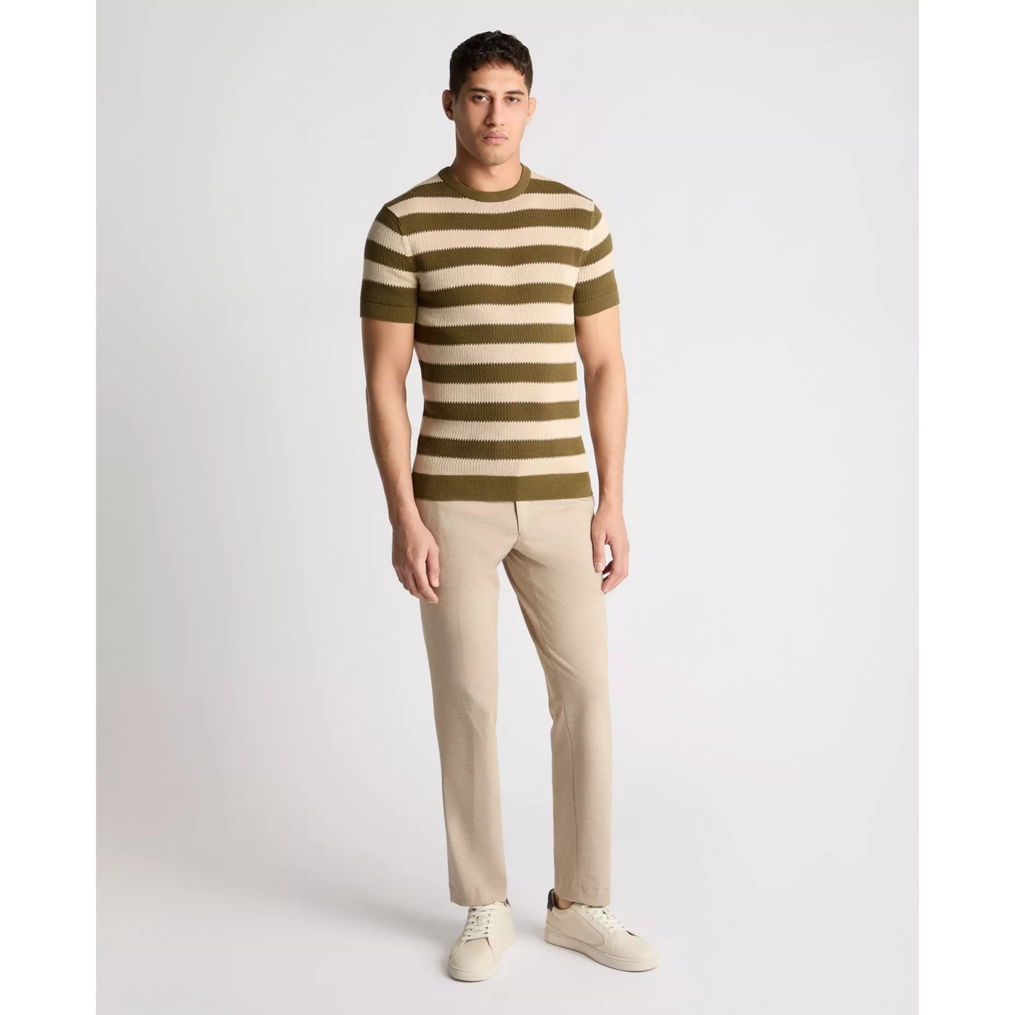 Man wearing a striped sweater and beige pants on a white background
