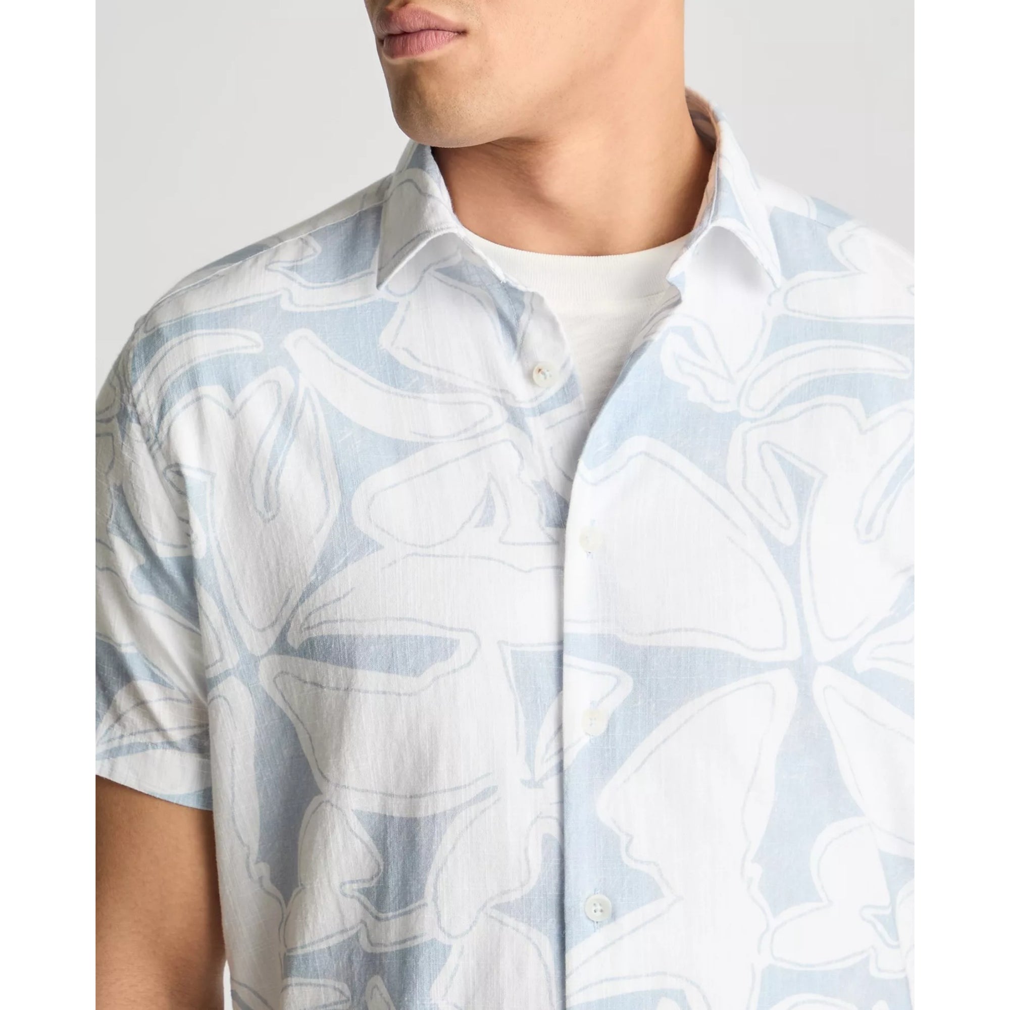 Man wearing a light blue floral patterned shirt against a white background