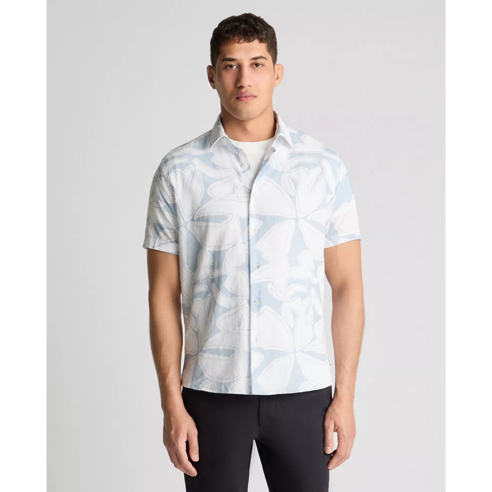 Man wearing a light blue patterned shirt on a gray background
