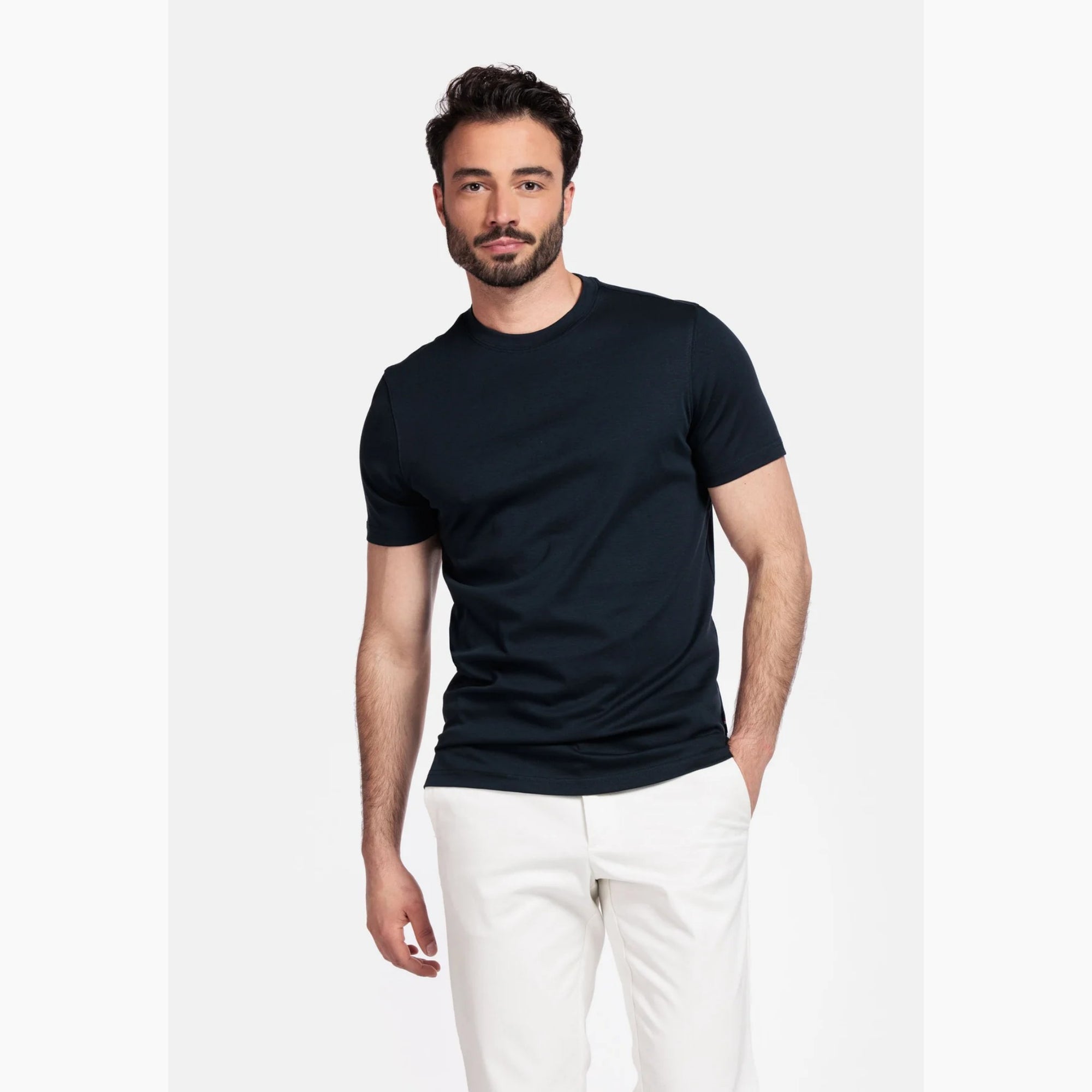 Man wearing a Giordano navy t-shirt and white pants on a white background