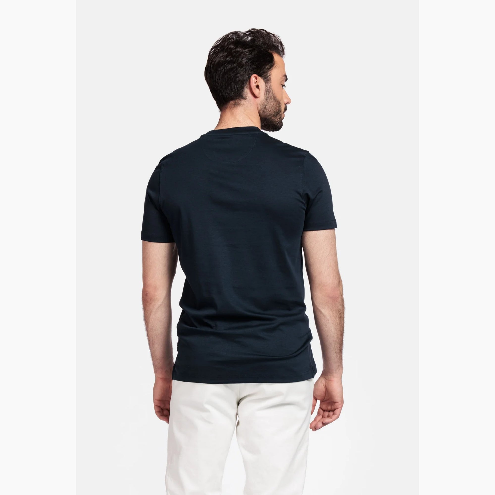 Man wearing a Giordano navy t-shirt and white pants on a white background
