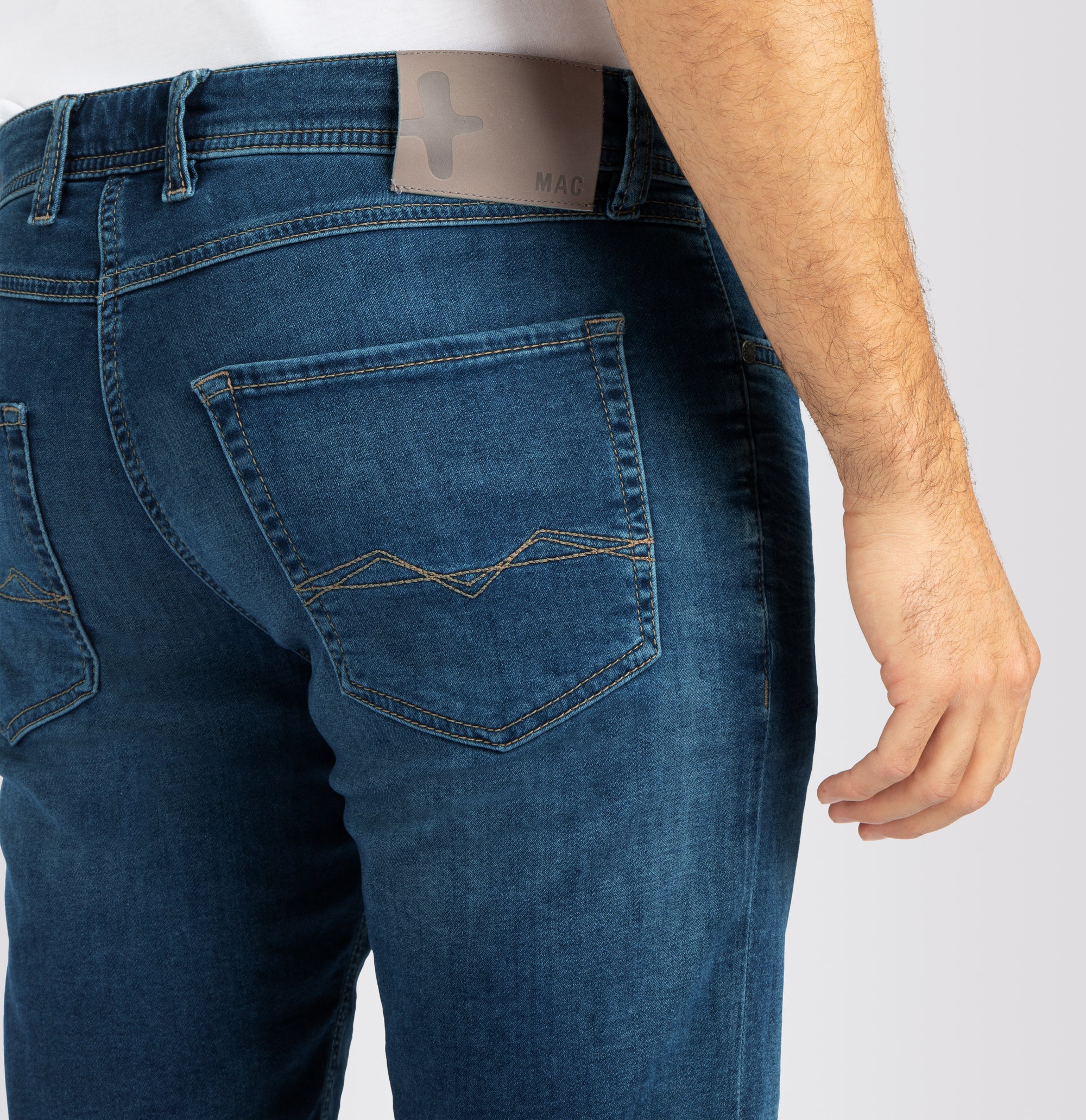 Close-up of blue jeans with a visible brand label on a white background