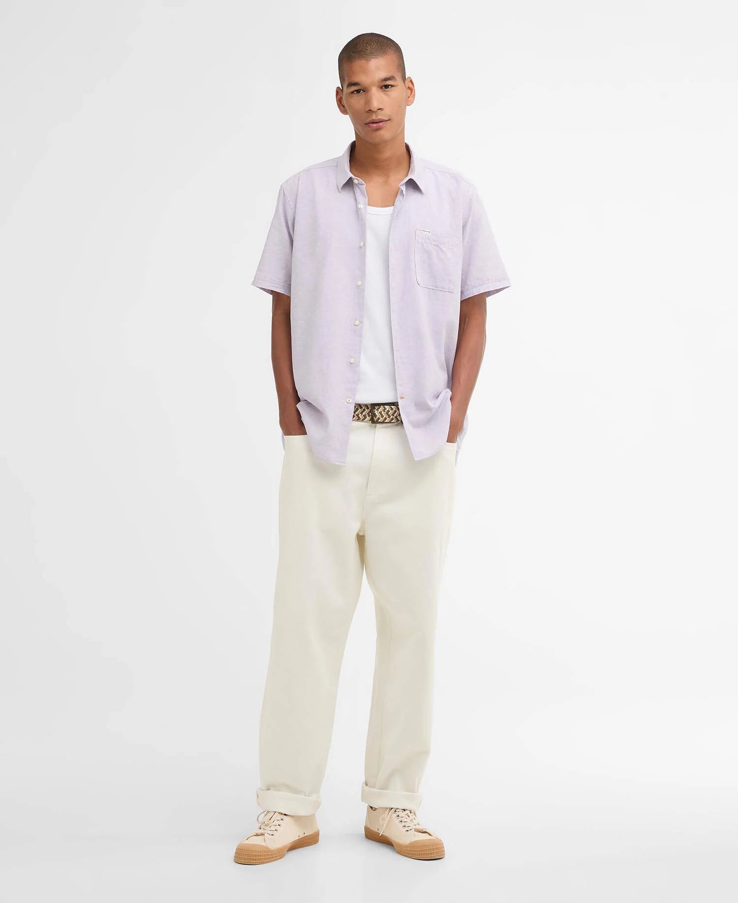 Man wearing a light purple shirt and beige pants on a white background