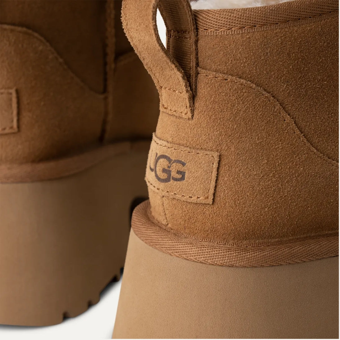 A chestnut brown UGG Classic Ultra Mini New Heights Boot with a suede upper and a chunky platform heel.