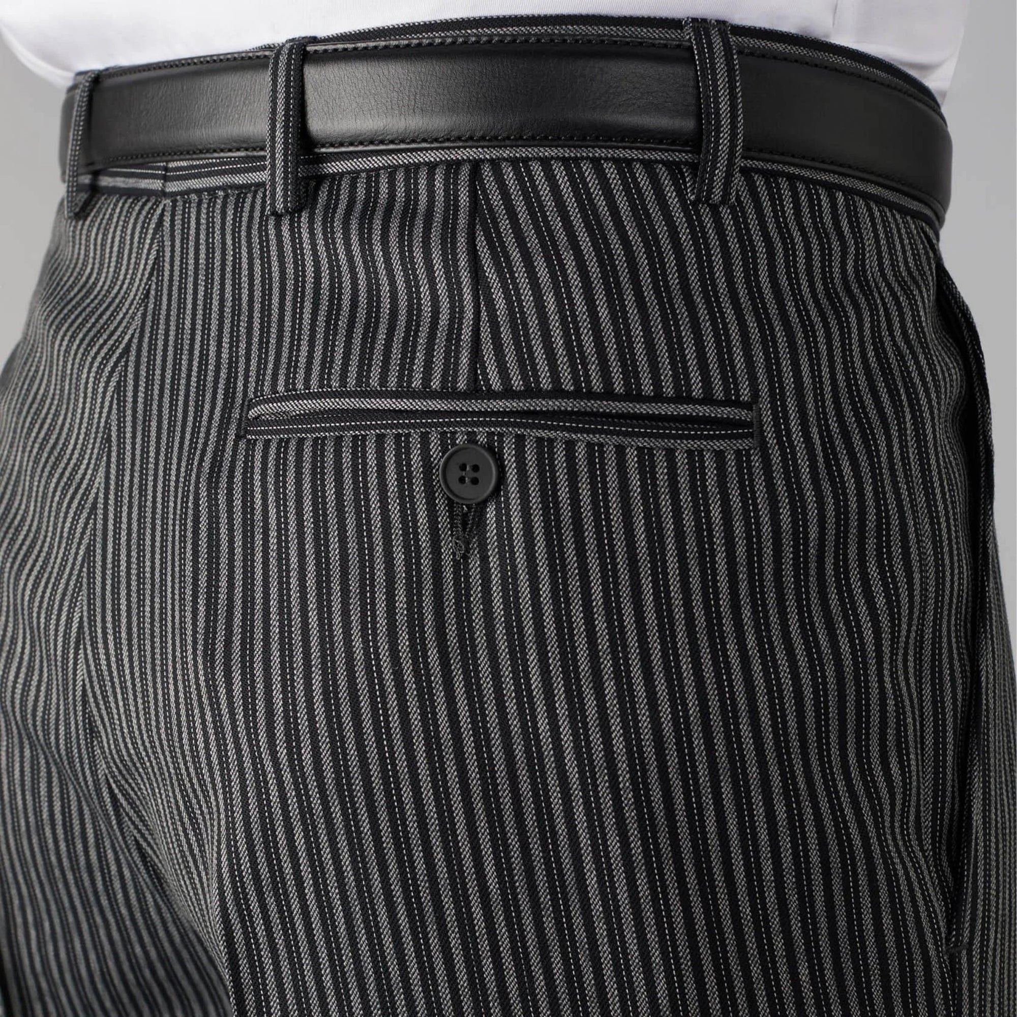Close-up of a person wearing black pinstripe pants with a white shirt and black belt.