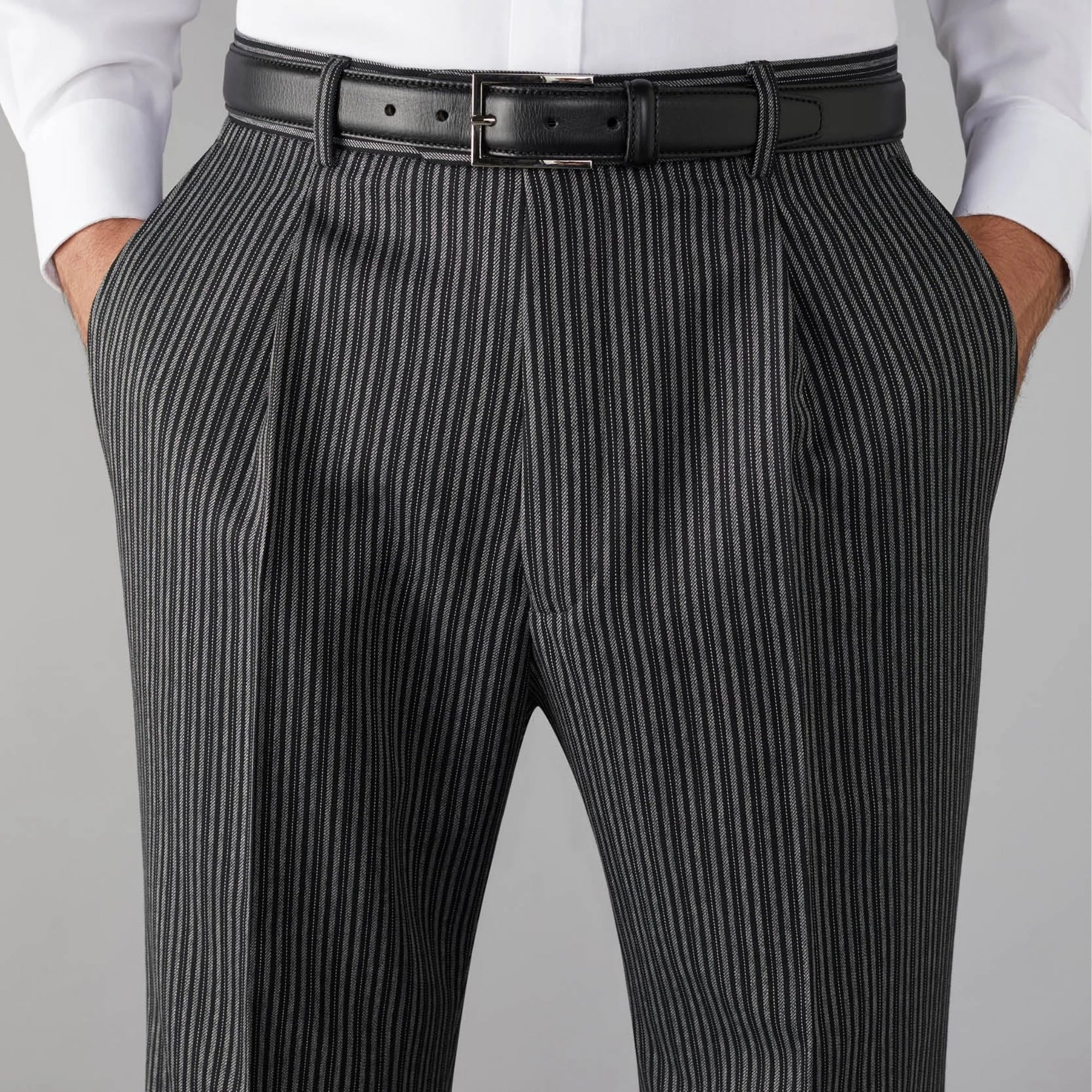 Black pinstripe pants with a black belt on a gray background