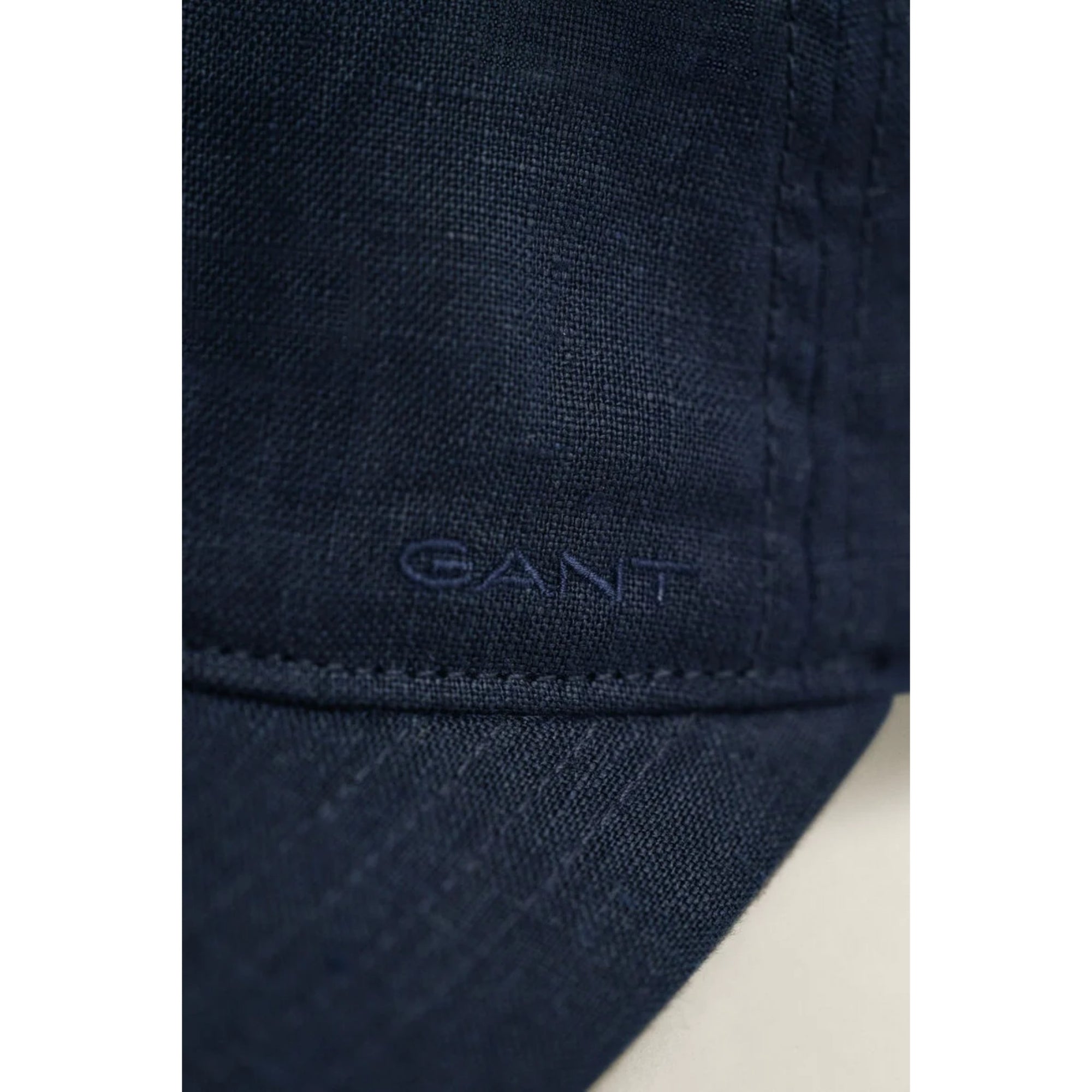 Close-up of dark blue fabric with 'Gant' logo on a white background