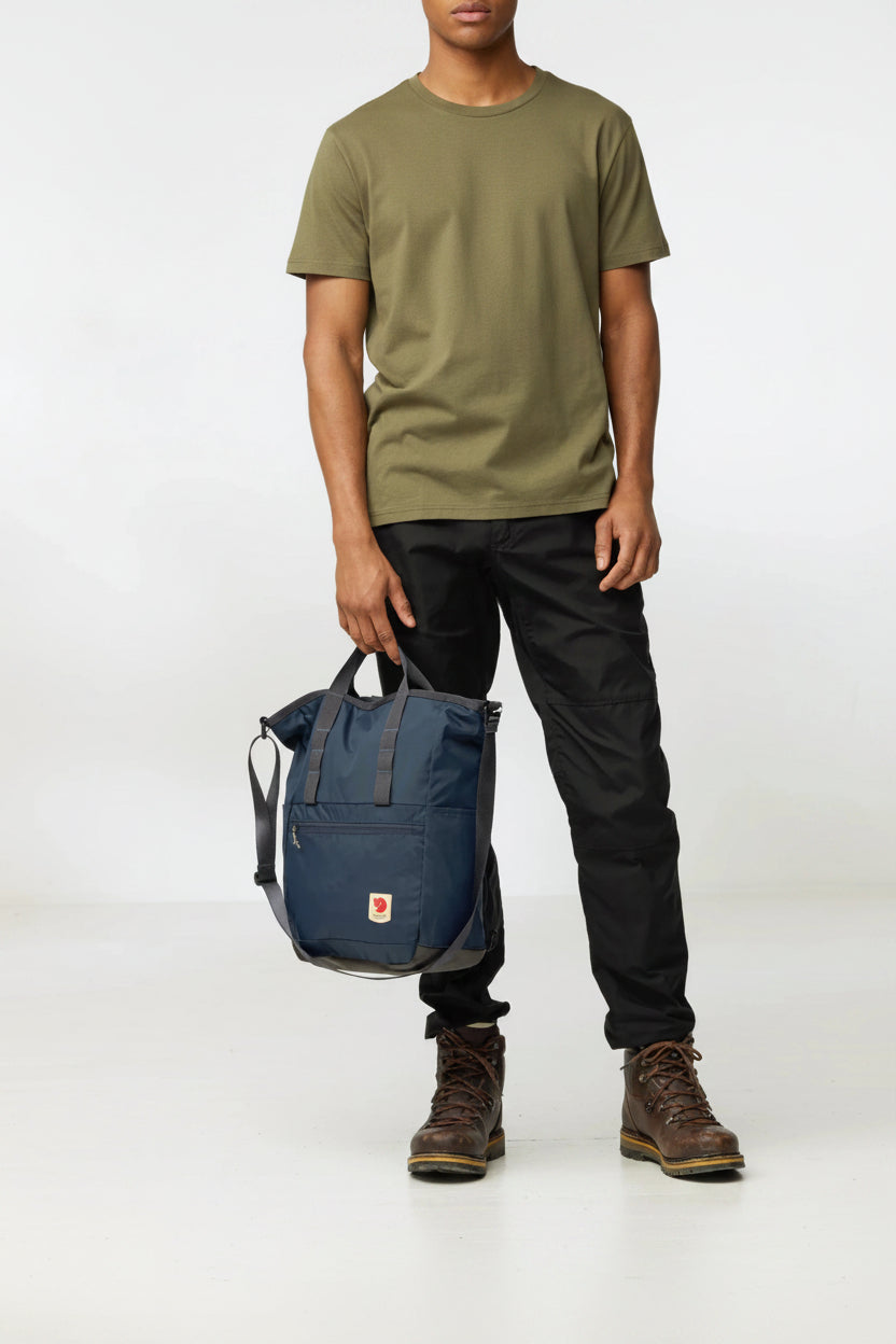 Person holding a navy blue backpack with a white background