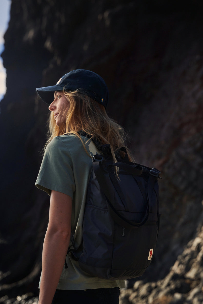Person with a backpack standing against a rocky wall