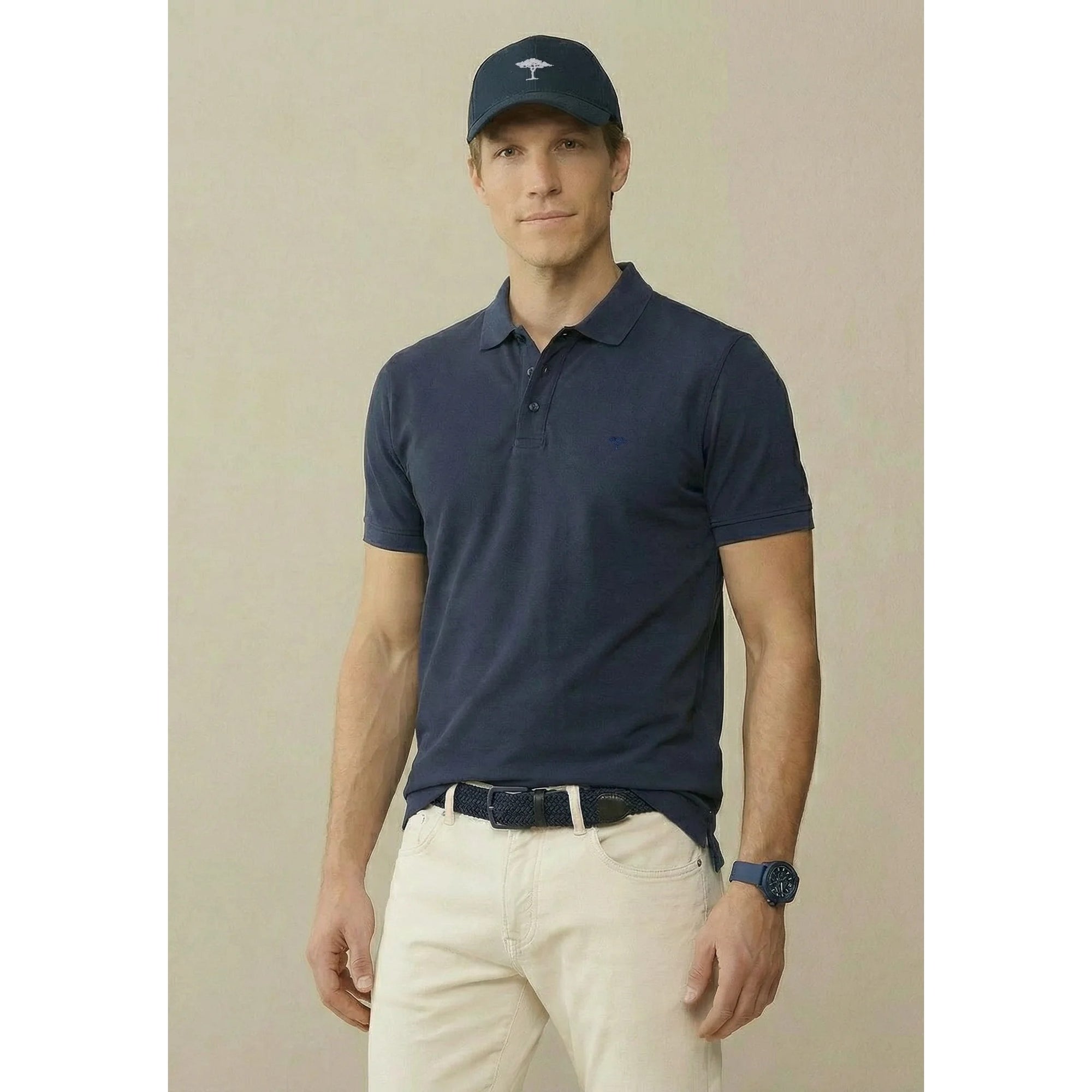 Man wearing a navy polo shirt and cap against a beige background