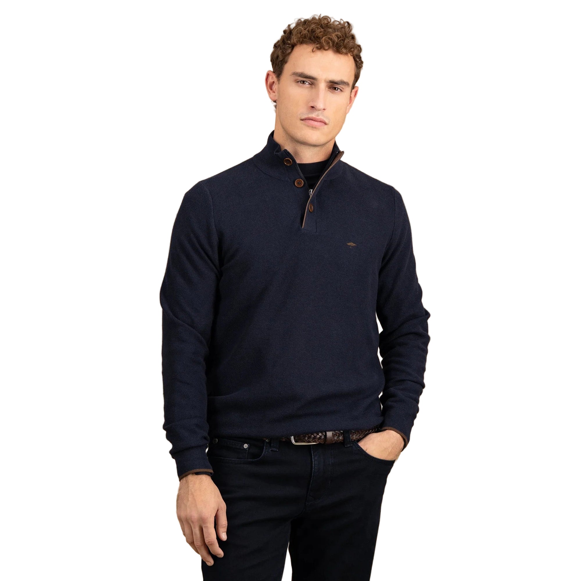Man wearing a navy blue sweater with a brand logo on a beige background