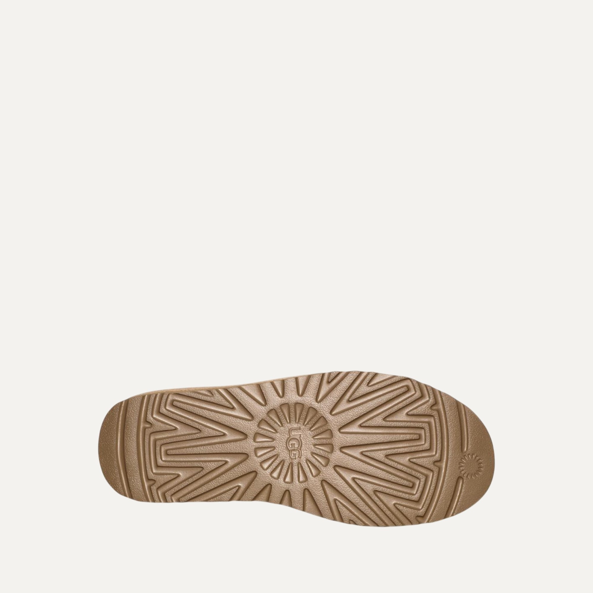 Close-up of a brown shoe sole with a brand logo on a light beige background