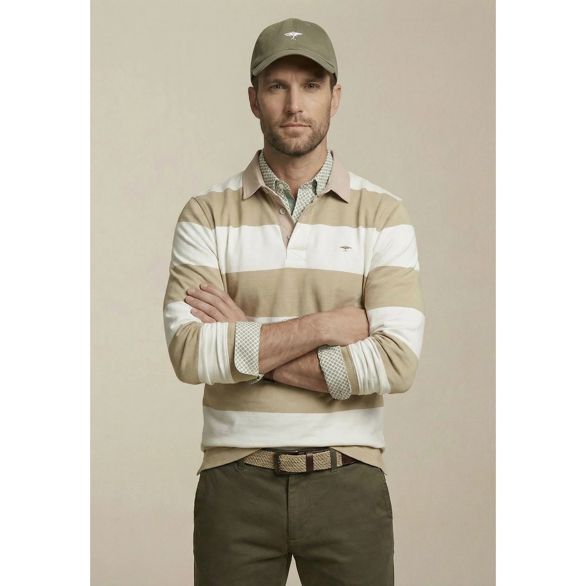 Man wearing a striped sweater and cap with a neutral background
