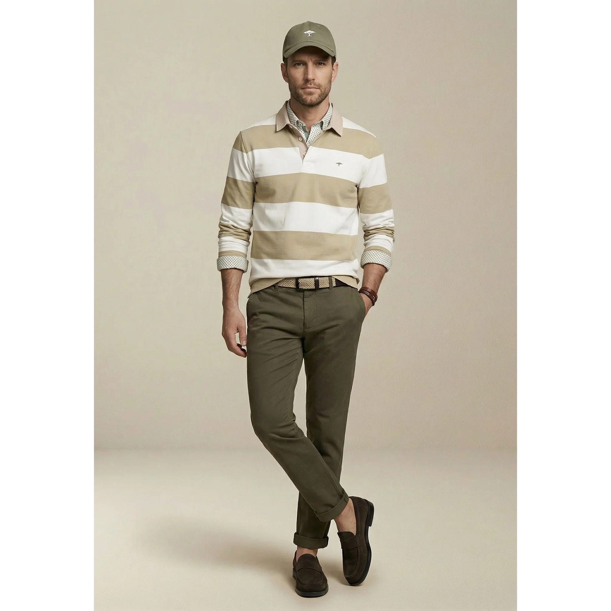Man wearing a striped polo shirt, cap, and pants on a beige background