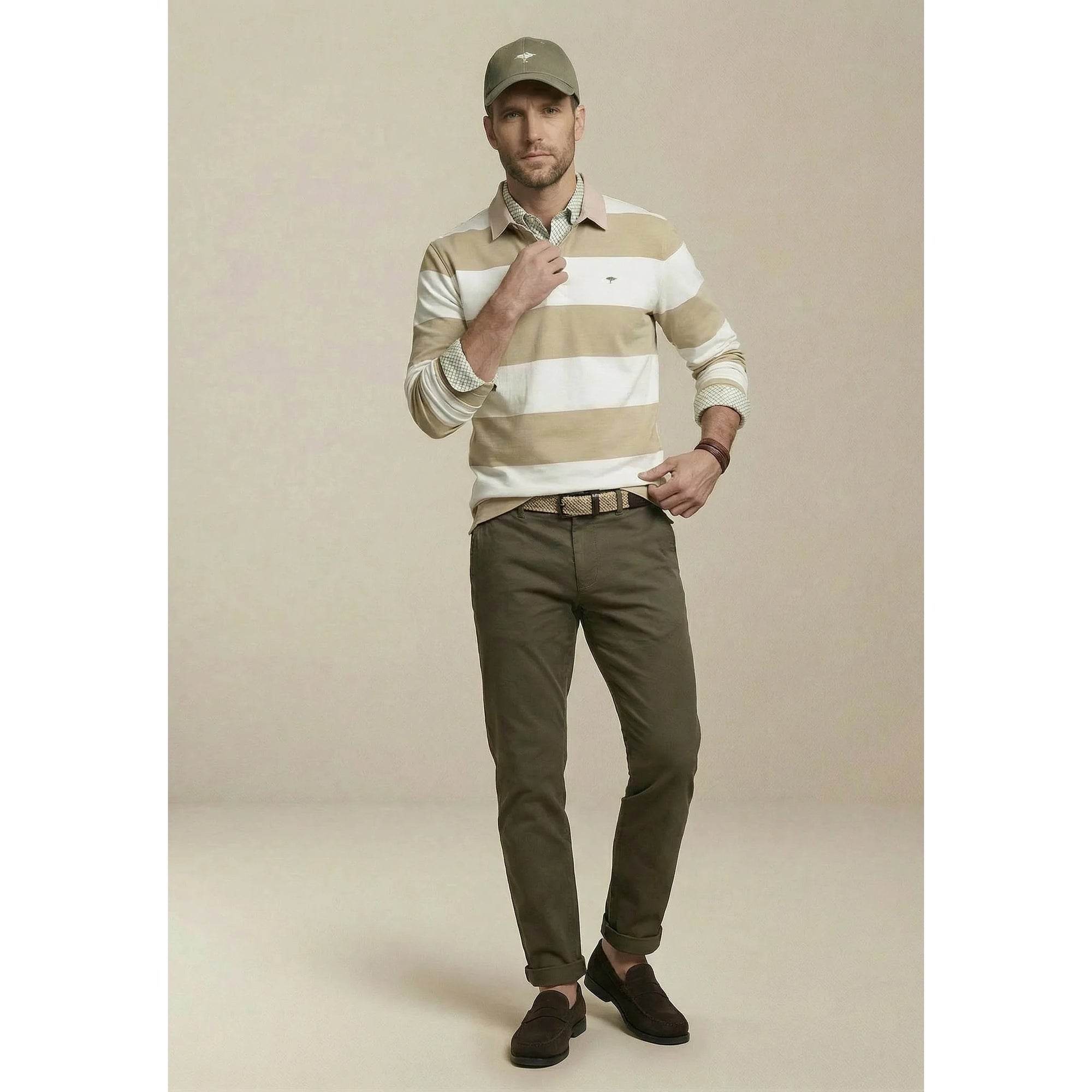 Man wearing a striped sweater, cap, and pants on a beige background
