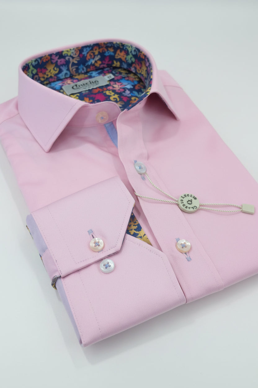Pink dress shirt with decorative buttons on a patterned fabric background