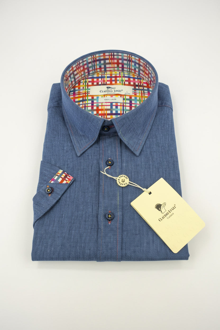 Folded blue shirt with a colorful plaid interior on a wooden surface, featuring a tag.