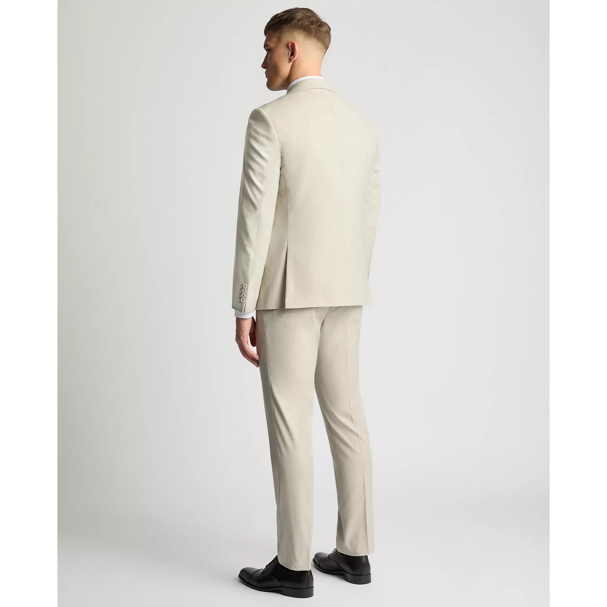 Man wearing a beige suit standing against a white background