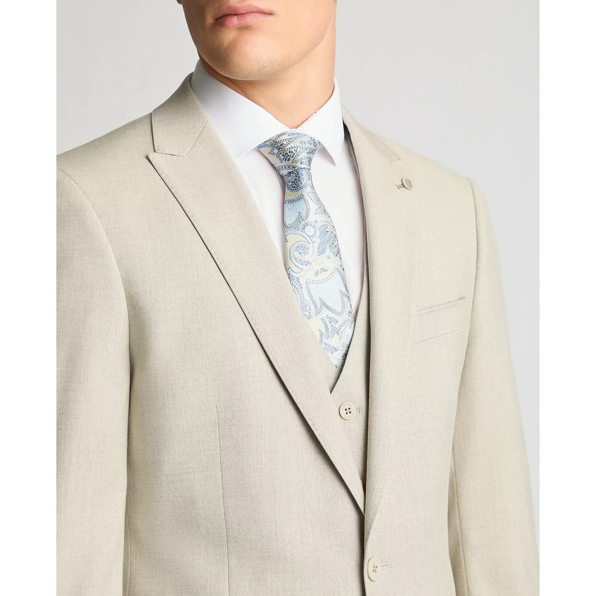 Beige suit with a white shirt and patterned tie on a light gray background