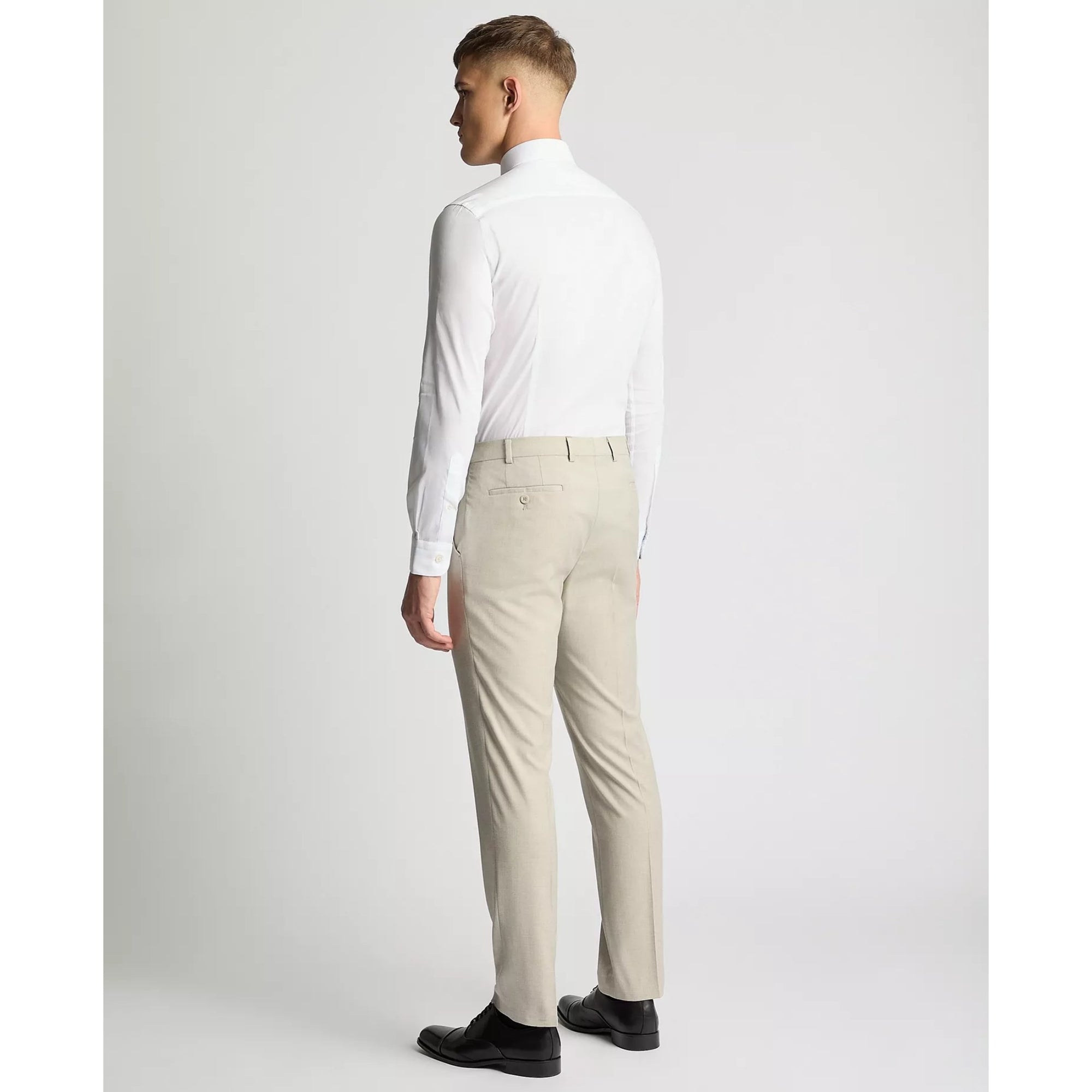 Man wearing a white shirt and beige pants on a plain background