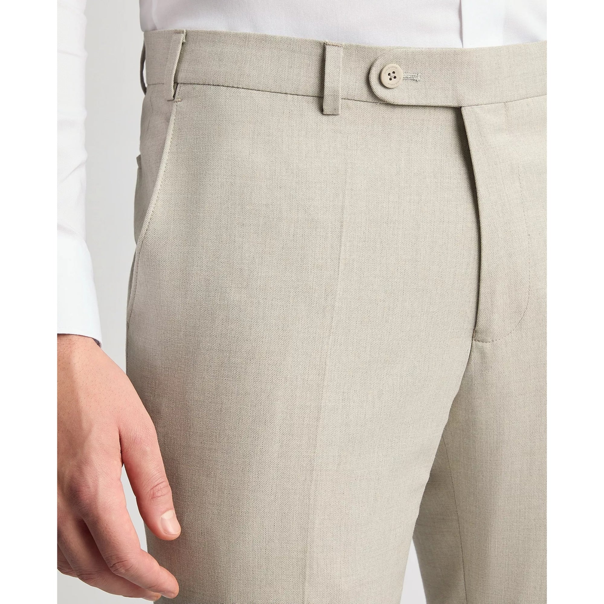 Close-up of beige dress pants with a white shirt underneath on a light gray background