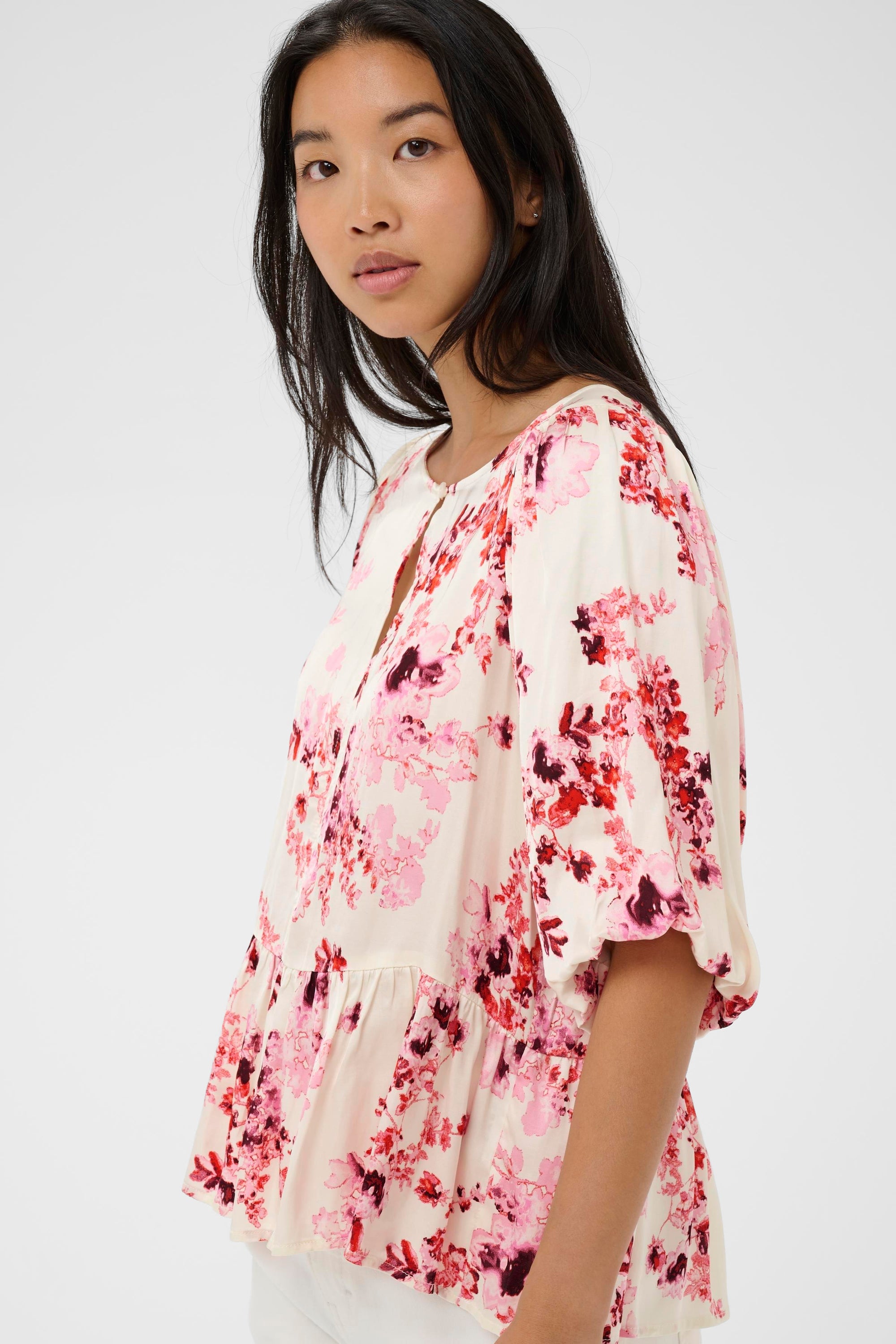 Woman wearing a floral blouse against a plain background