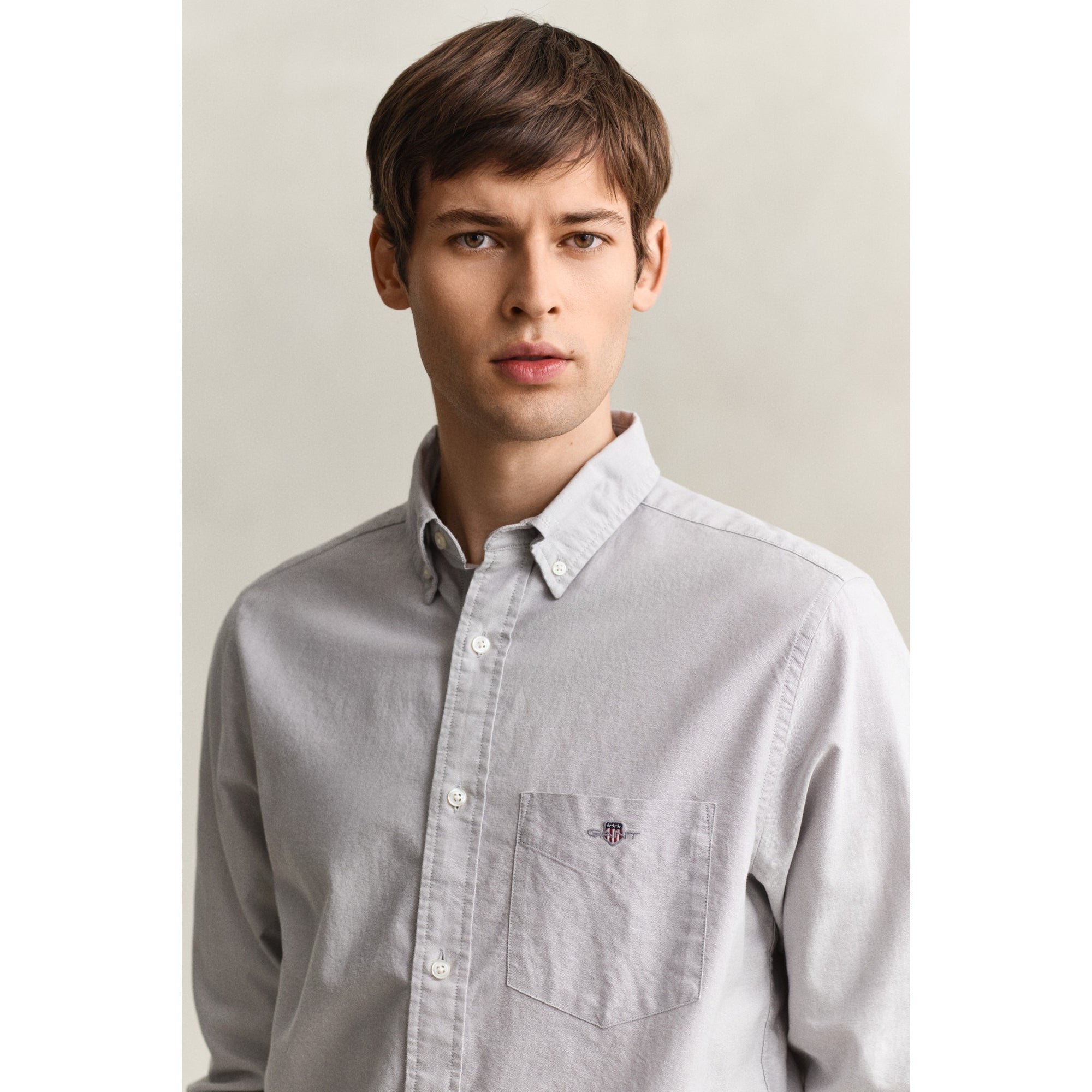 Man wearing a light gray button-up shirt against a plain background