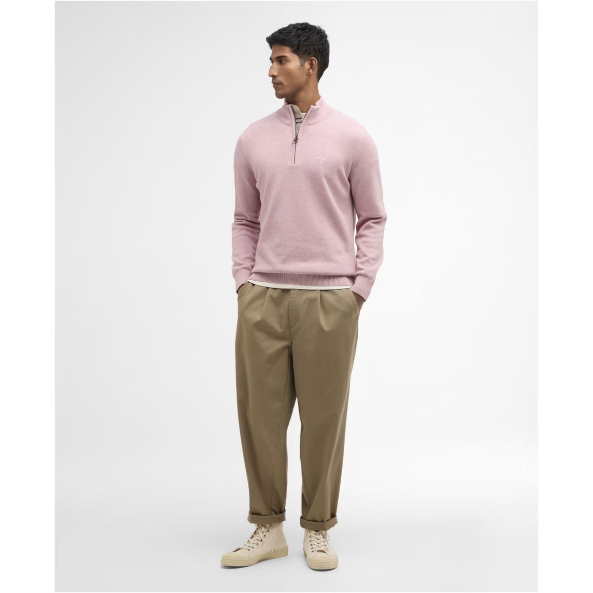 Man wearing a pink sweater and beige pants on a white background