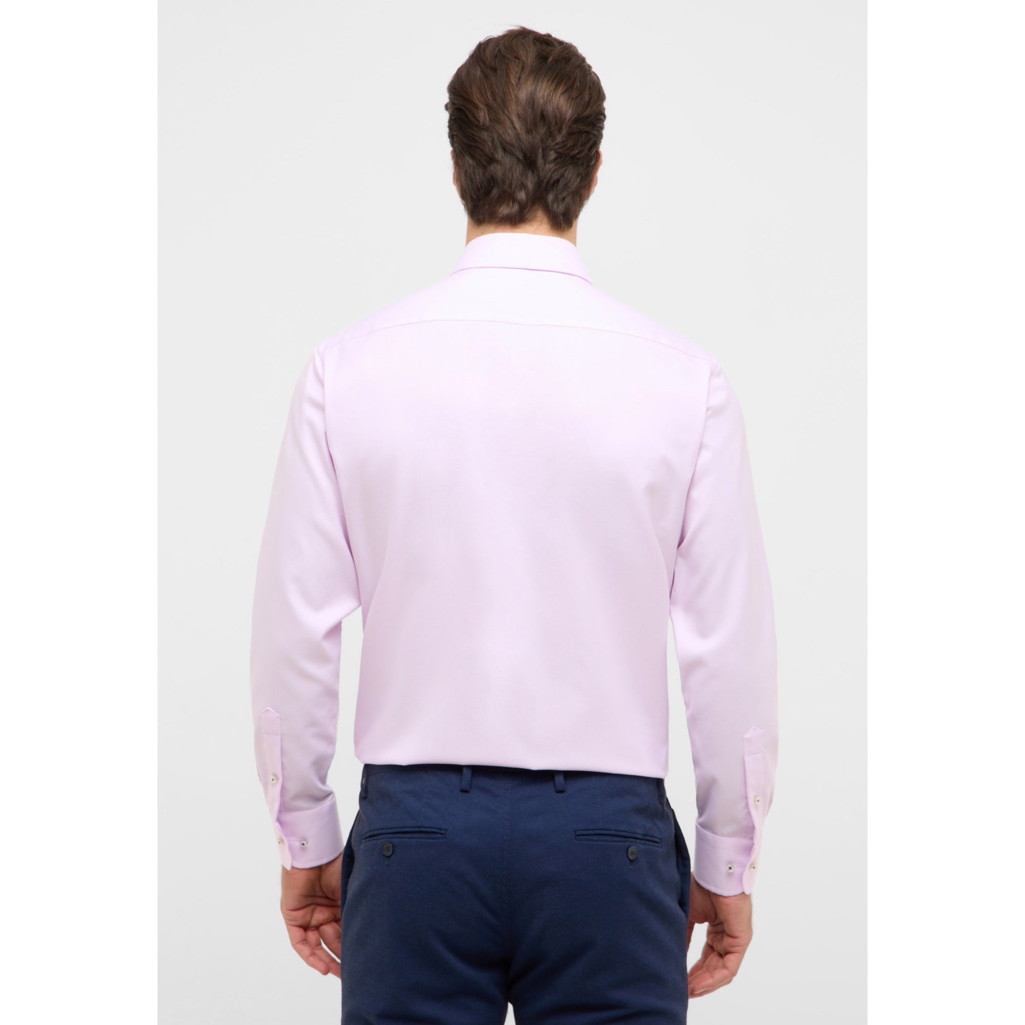 Man wearing a light purple dress shirt and navy pants on a white background