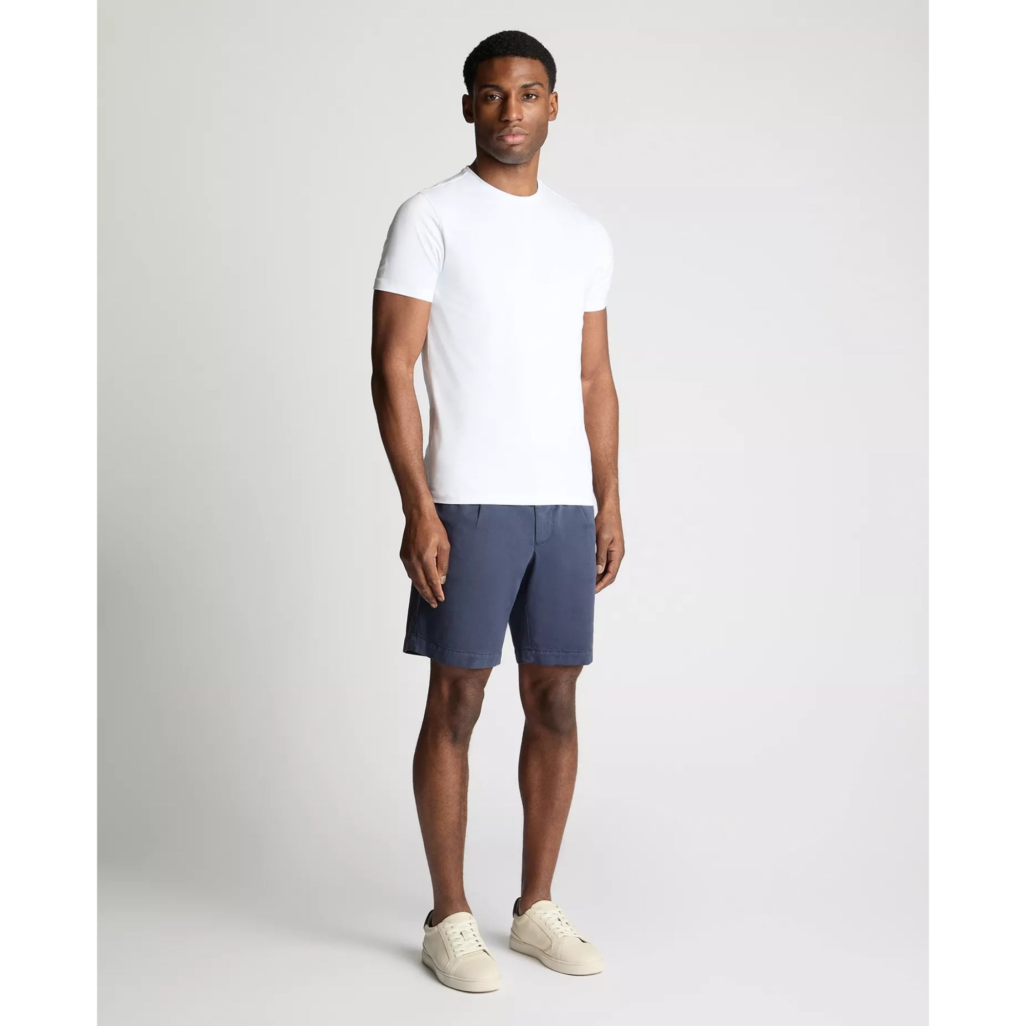 Man wearing a white t-shirt and blue shorts on a plain background