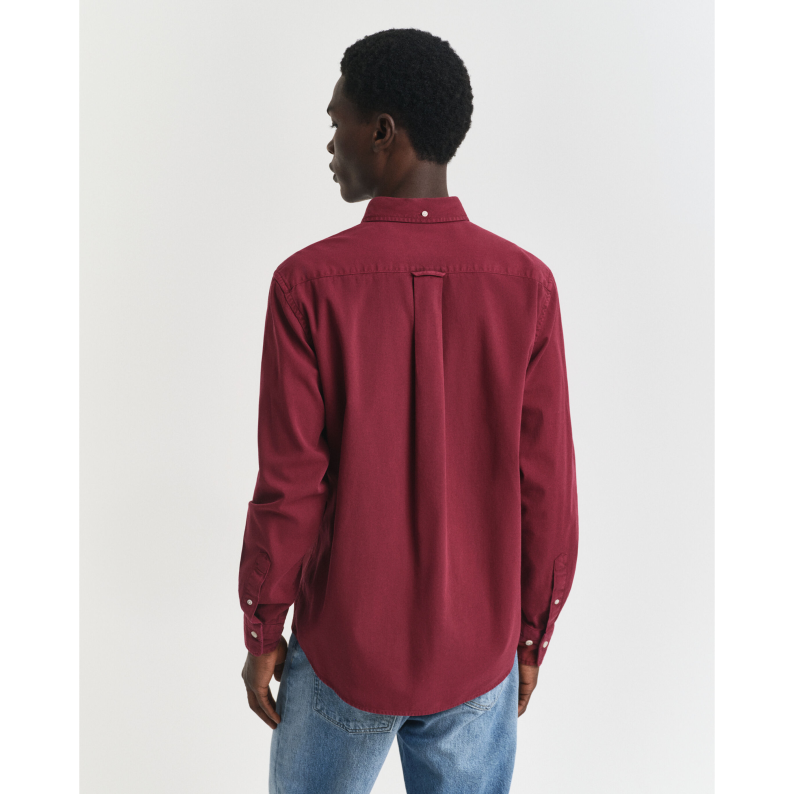 Person wearing a GANT  red shirt and blue jeans on a white background