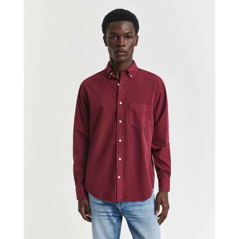Man wearing a GANT red button-up shirt and light blue jeans on a white background