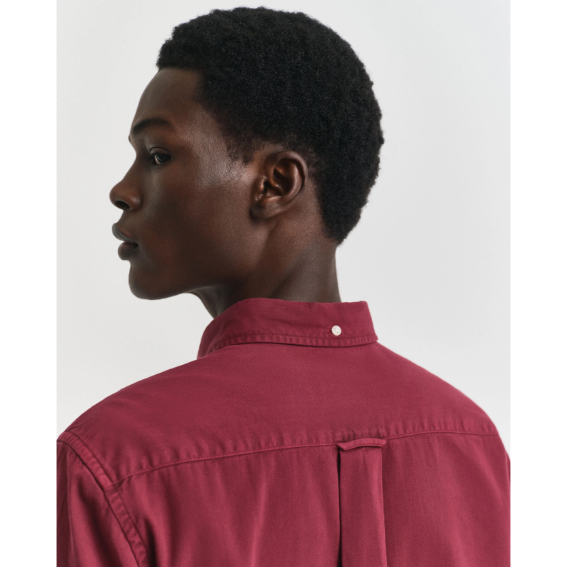 Person wearing a GANT red shirt against a plain background