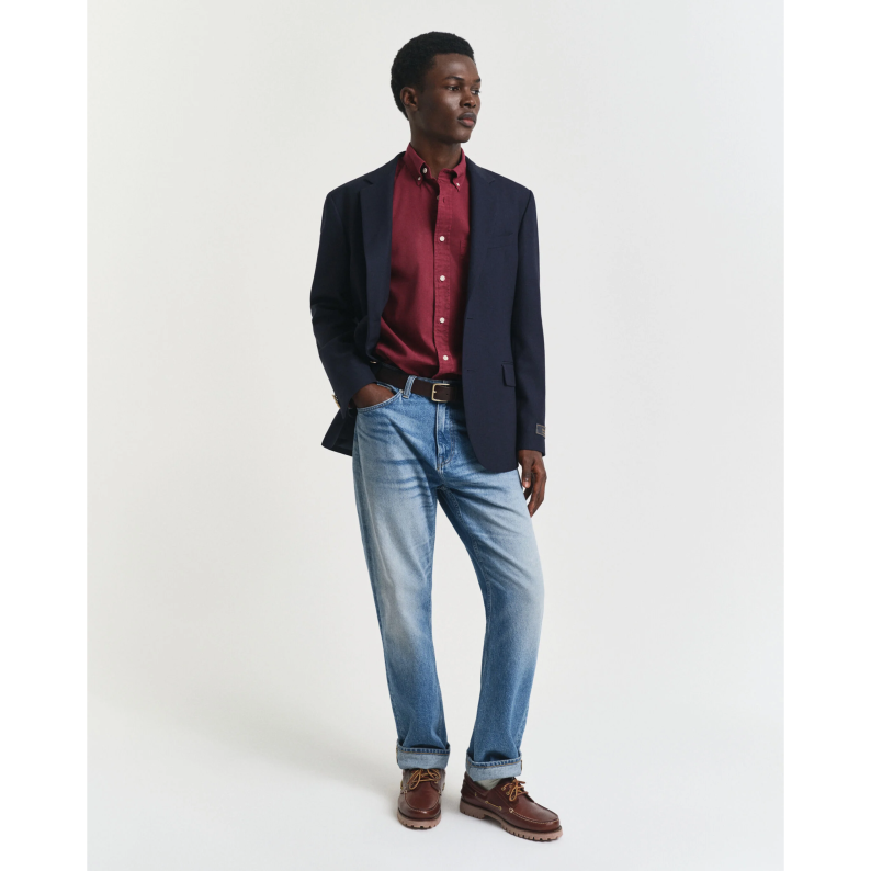 Man wearing a GANT navy blazer, red shirt, and blue jeans on a white background