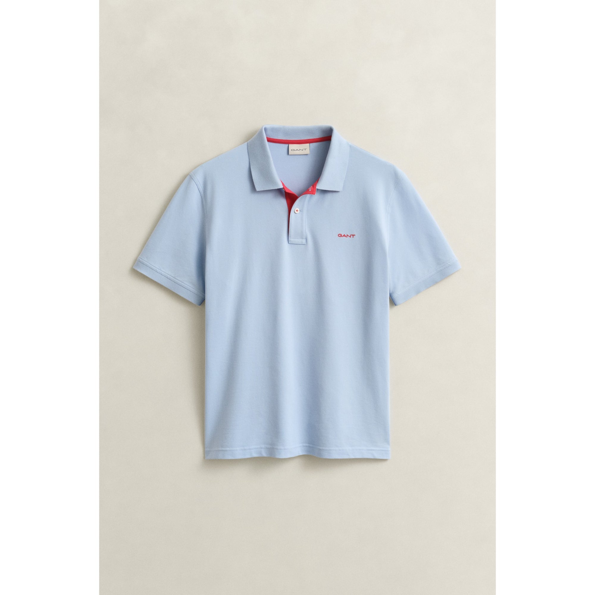 Light blue polo shirt with red collar on a beige background