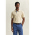 Man wearing a beige polo shirt and blue pants against a neutral background