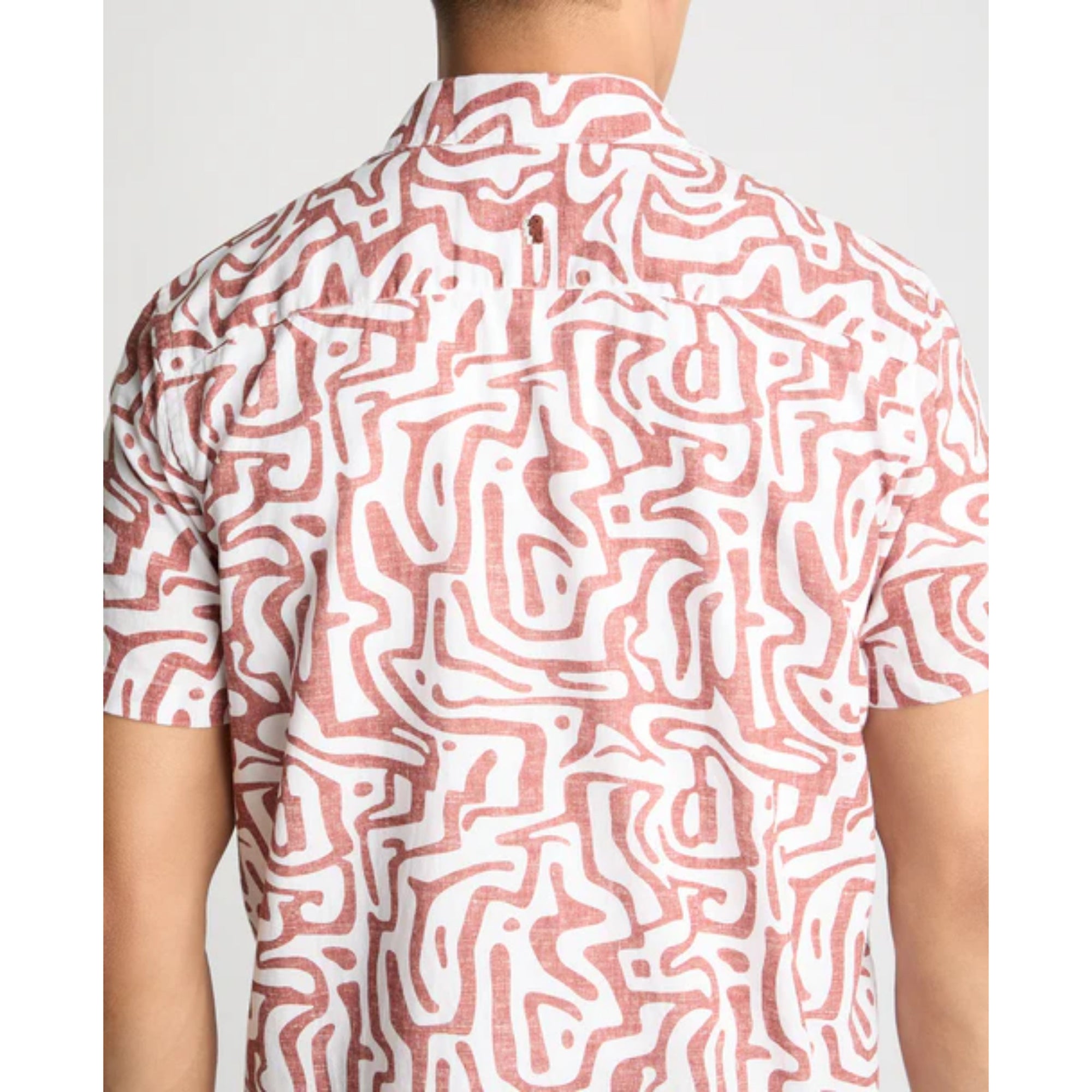 Person wearing a shirt with a red and white abstract pattern on a plain background