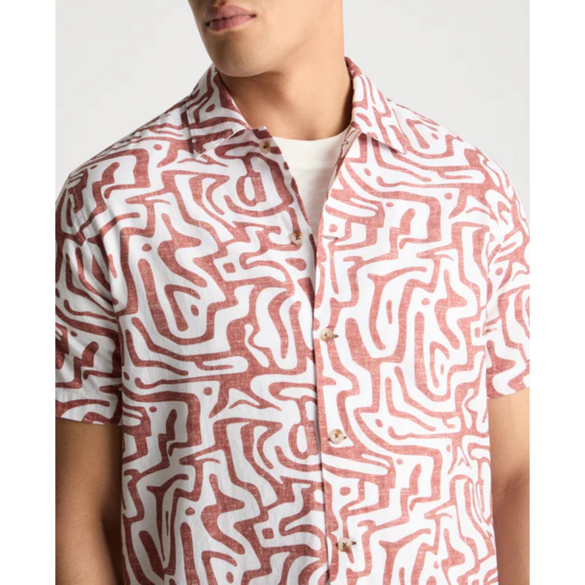 Person wearing a patterned shirt with wavy lines on a plain background