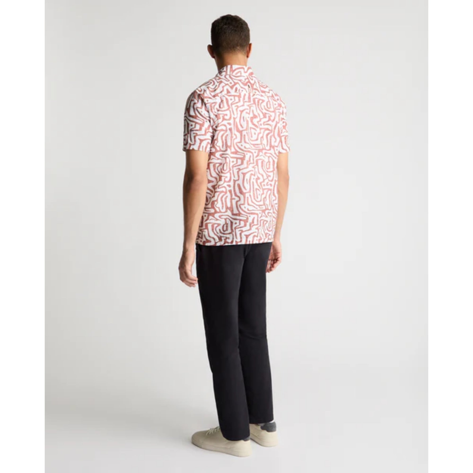 Person wearing a patterned shirt and black pants on a white background