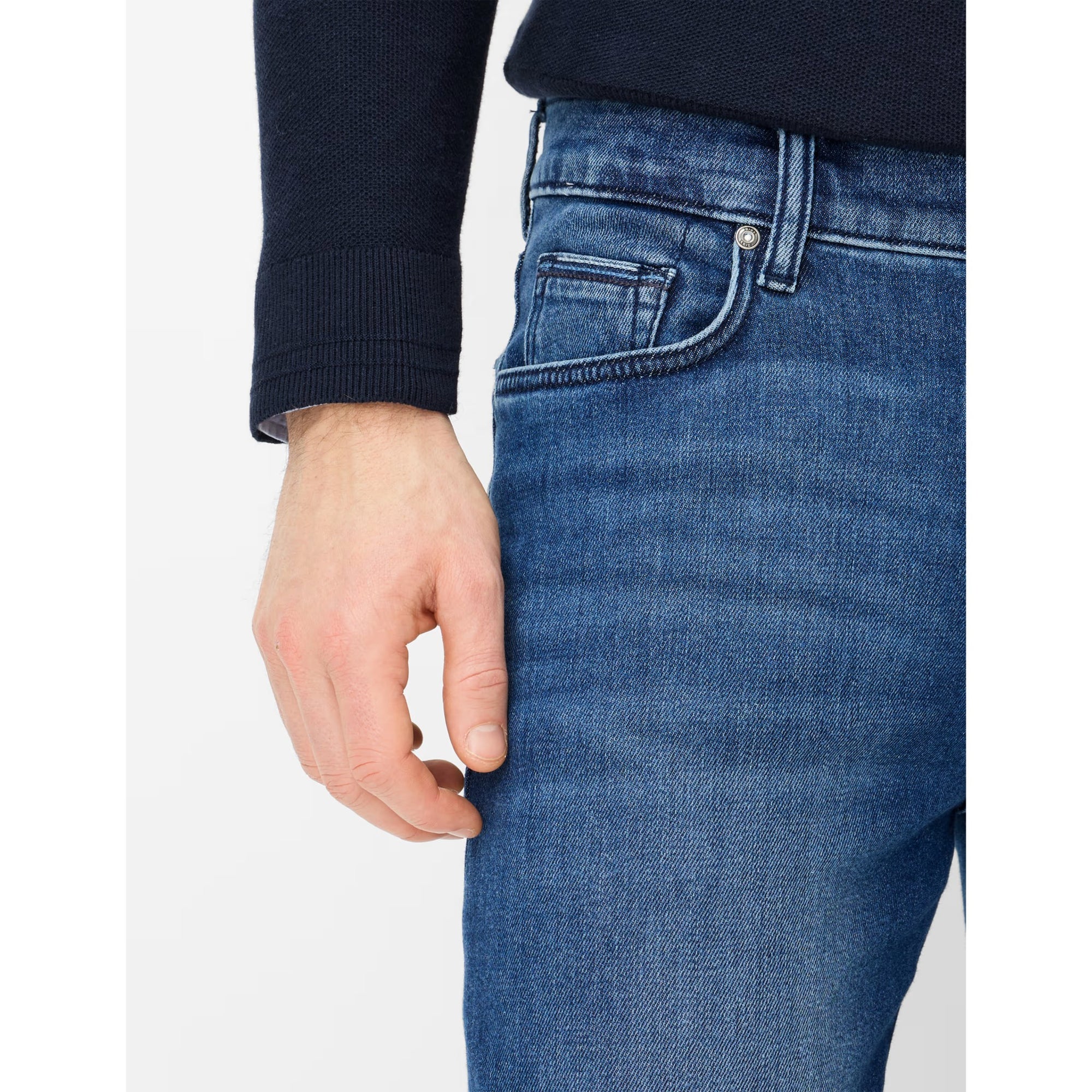 Close-up of blue jeans with a hand adjusting the waistband on a white background