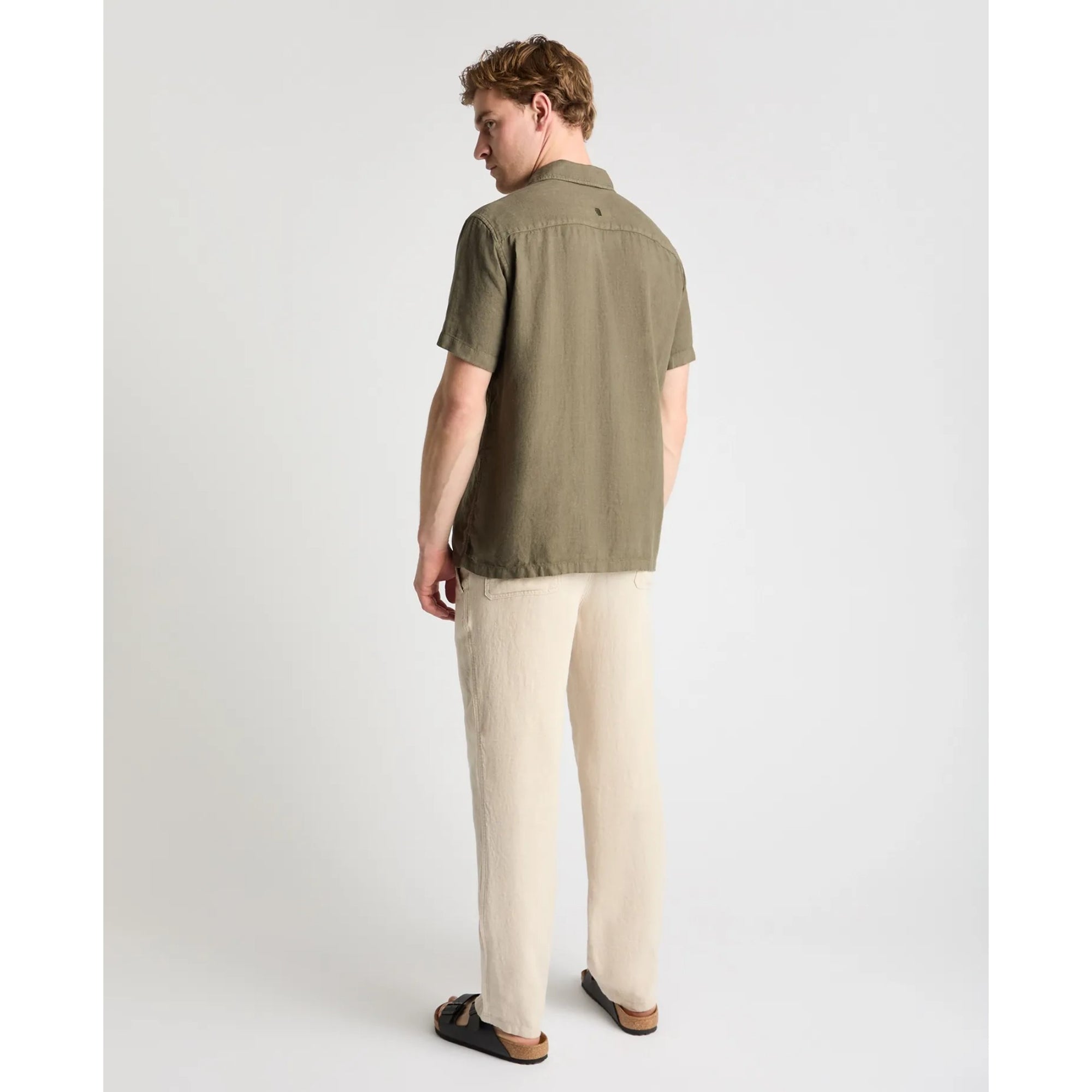 Man wearing a green shirt and beige pants on a white background