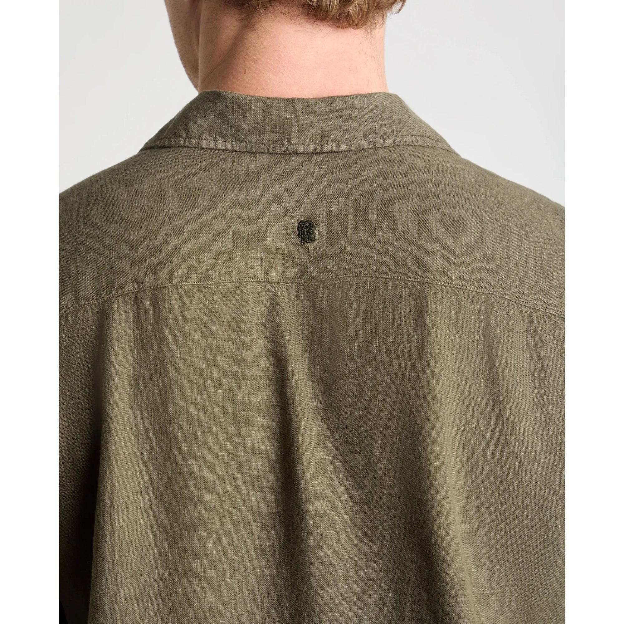 Olive green shirt worn by a person on a white background