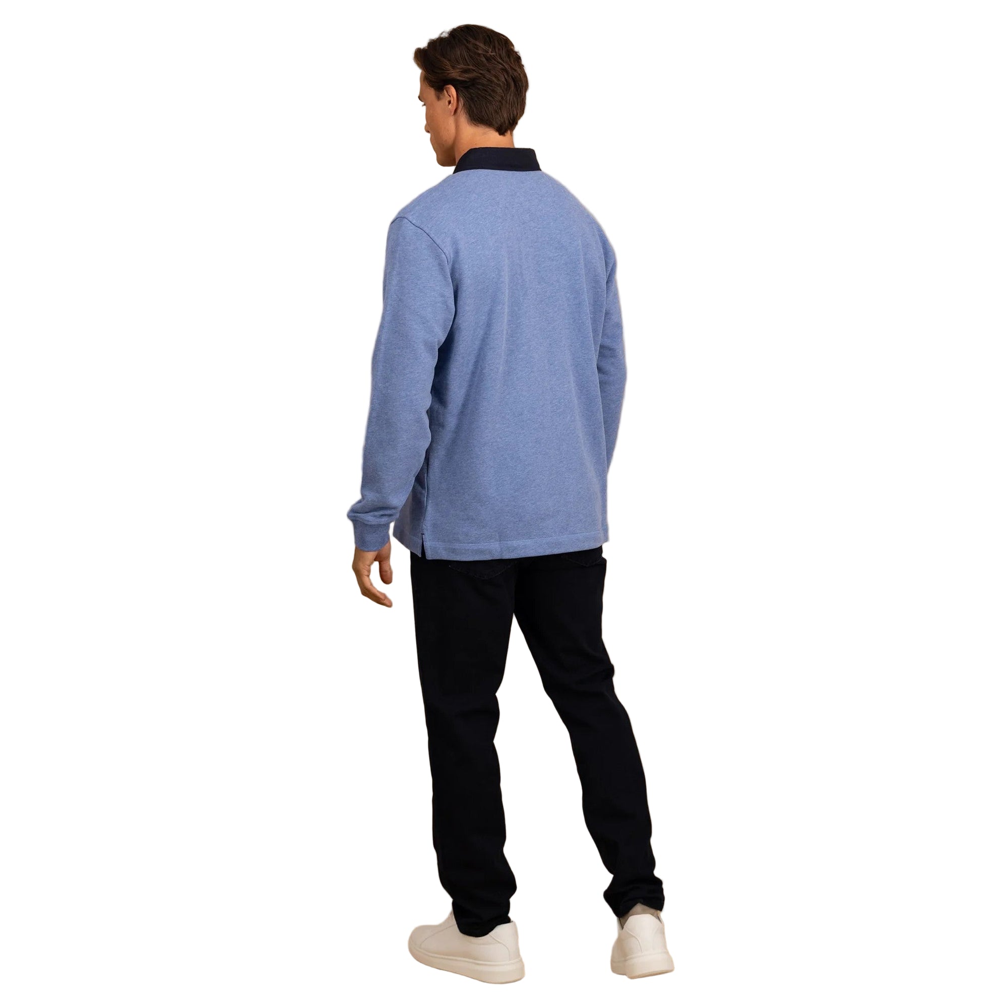 Man wearing a blue sweater and black pants against a beige background