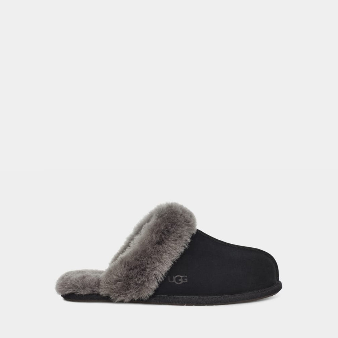 Black UGG slipper with beige fur lining on a light gray background