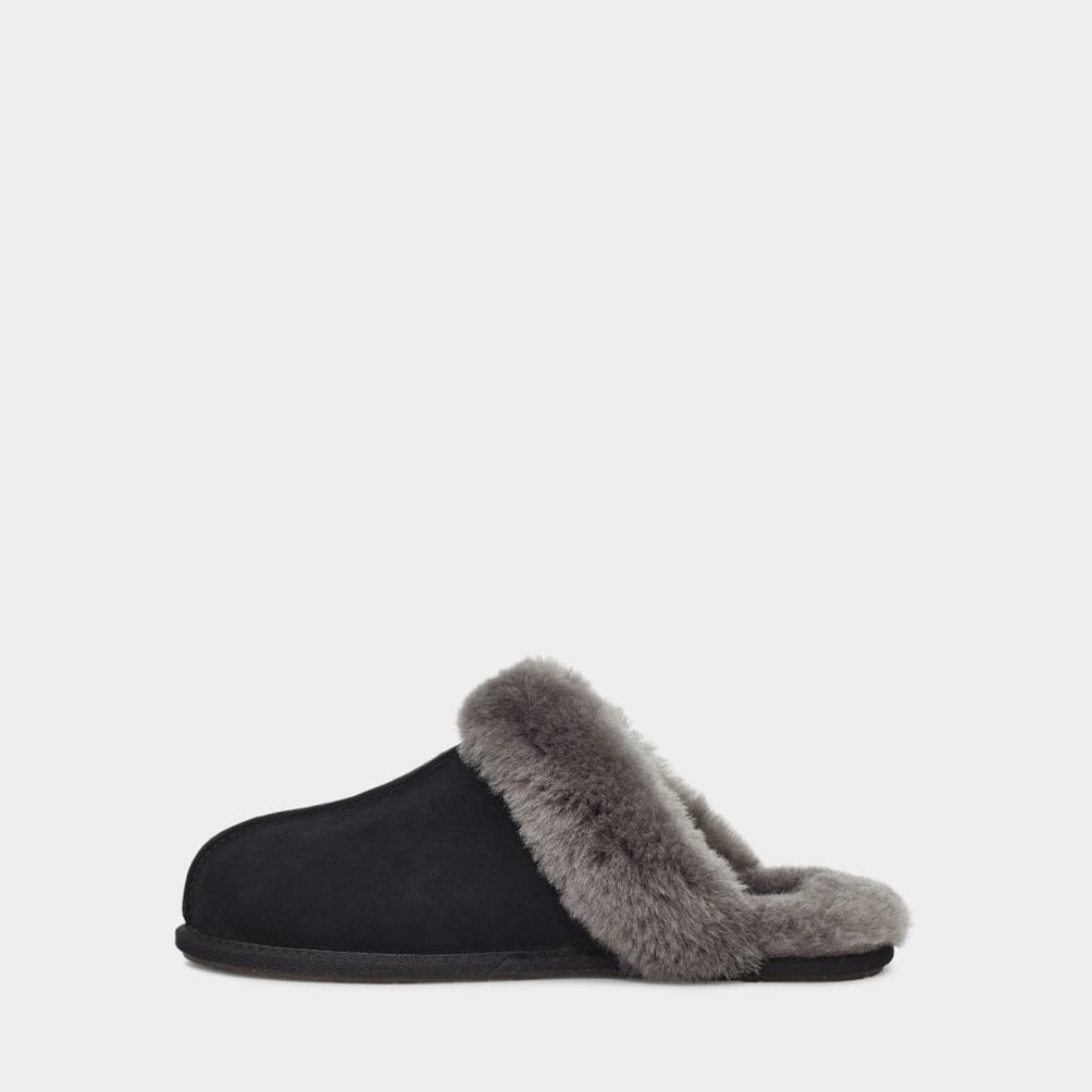 Black UGG slipper with beige fur lining on a light gray background