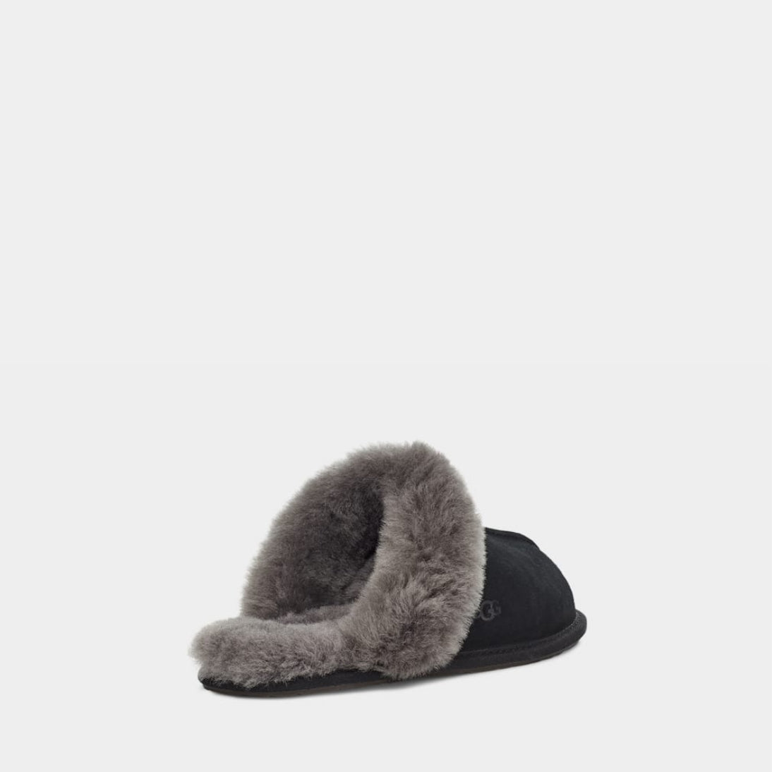 Black UGG slipper with beige fur lining on a light gray background