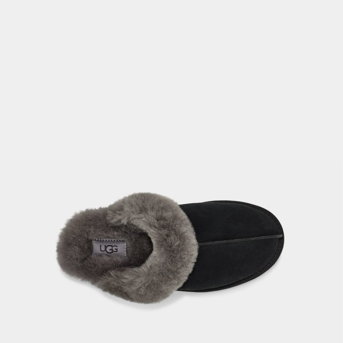 Black UGG slipper with beige fur lining on a light gray background
