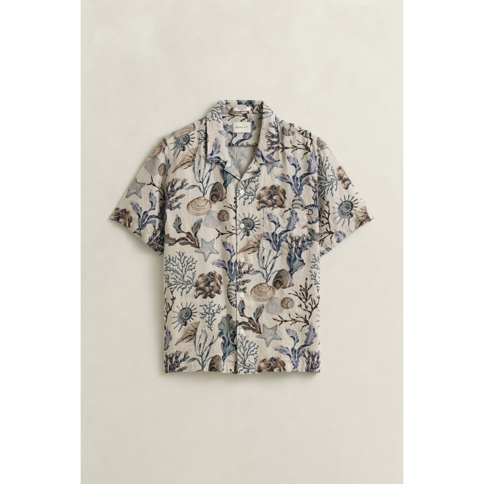Short-sleeve shirt with nature-themed pattern on a beige background