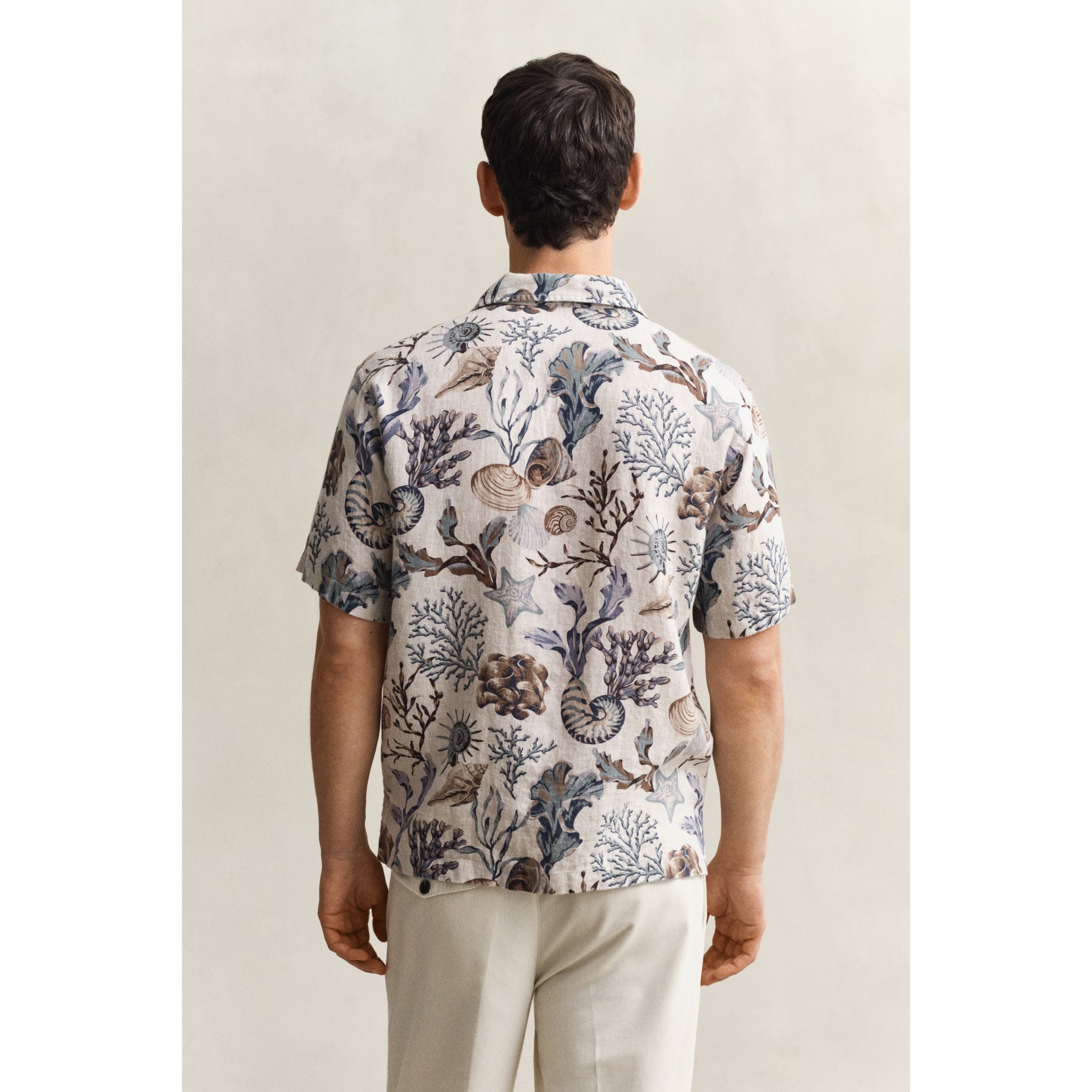 Man wearing a patterned shirt with a neutral background