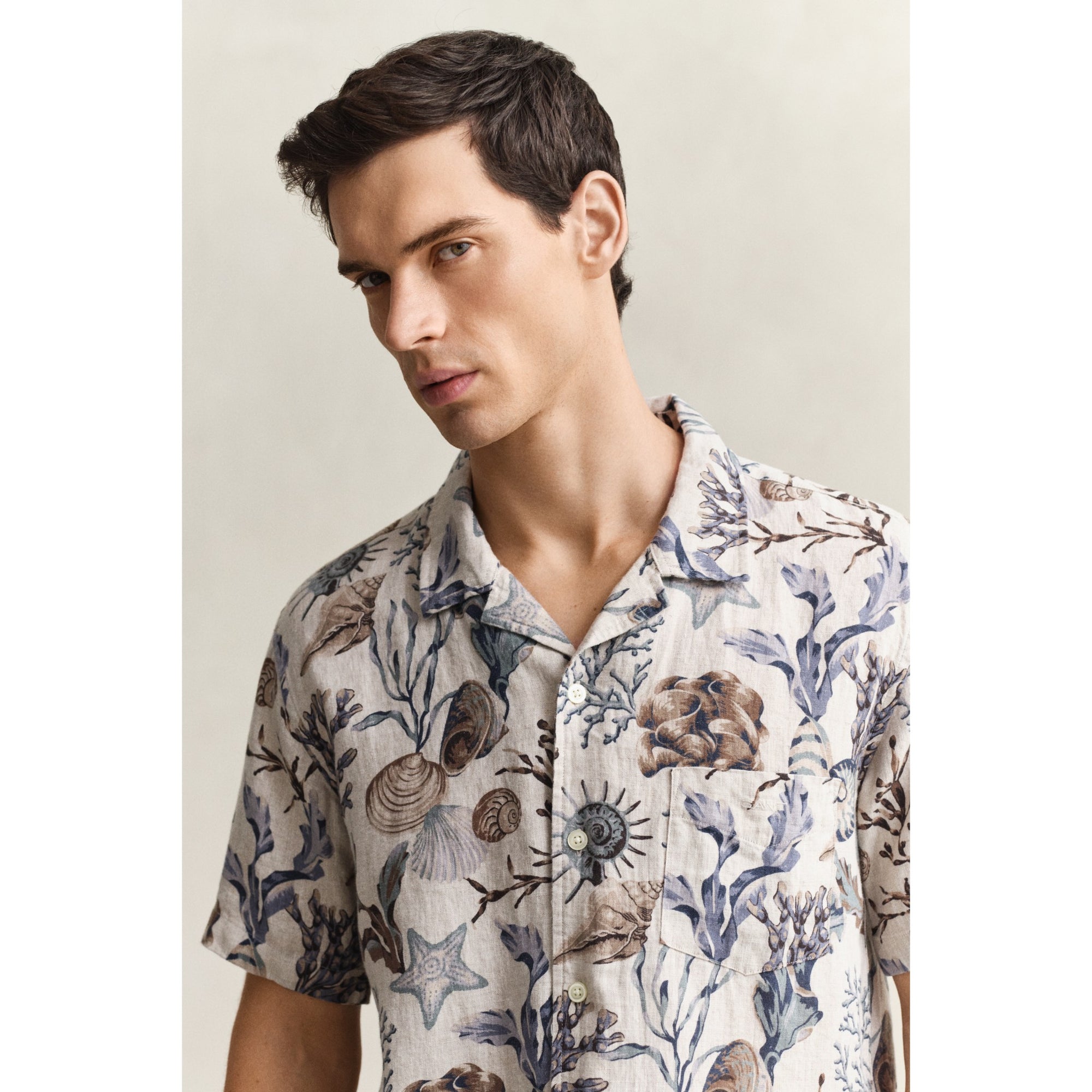 Man wearing a patterned shirt with nature-themed design on a plain background